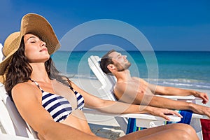 Happy couple relaxing on deck chair at the beach