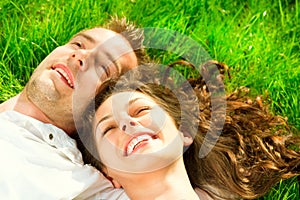 Happy couple relaxing on green grass