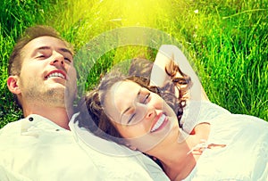 Happy couple relaxing on green grass