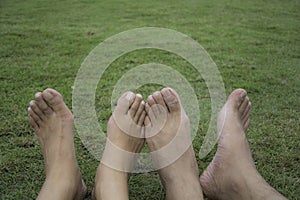 Happy couple relaxing on green grass. Couple lying on grass outdoor. Barefoot. Asian male and female.