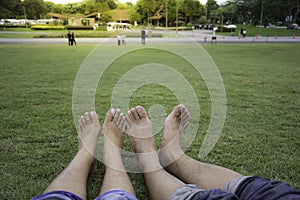 Happy couple relaxing on green grass. Couple lying on grass outdoor. Barefoot. Asian male and female, in a favorite p