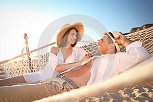Happy couple relaxing in hammock on beach