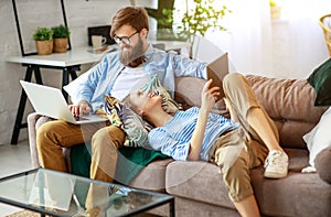 Happy couple relaxing at home with laptop and tablet