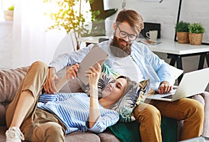 Happy couple relaxing at home with laptop and tablet