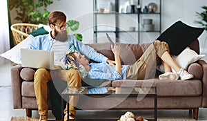 Happy couple relaxing at home with laptop and tablet