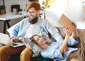 Happy couple relaxing at home with laptop and tablet