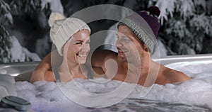 Happy couple relaxing in outdoor hot tub at winter in resort spa hotel. romantic getaway