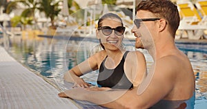 happy couple relaxing together in holiday resort swimming pool. summer vacation, romantic getaway