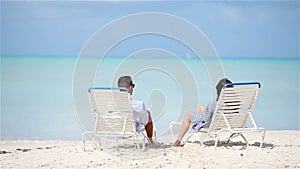 Happy couple relaxing on a tropical beach on sunbed