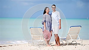 Happy couple relaxing on a tropical beach on sunbed