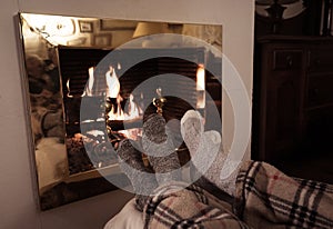 Happy couple relaxing under blanket by the fireplace warming up feet in woolen socks