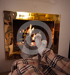 Happy couple relaxing under blanket by the fireplace warming up feet in woolen socks