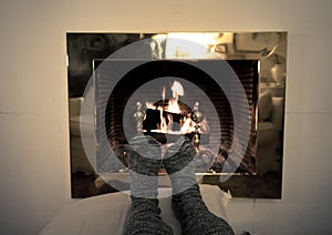 Happy couple relaxing under blanket by the fireplace warming up feet in woolen socks