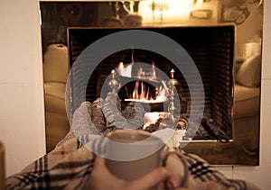 Happy couple relaxing under blanket by the fireplace warming up feet in woolen socks