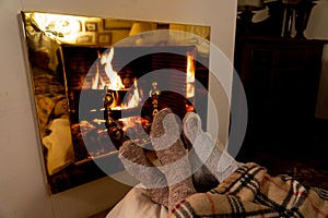 Happy couple relaxing under blanket by the fireplace warming up feet in woolen socks