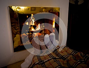 Happy couple relaxing under blanket by the fireplace warming up feet in woolen socks