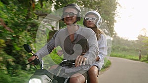 Happy couple ride on motorbike. Two lovers travel by motorcycle in tropics. Girlfriend, boyfriend drive scooter on