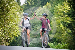 Happy couple ride on a mountain asphalt road on bikes