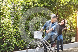Happy couple riding bicycle together in romantic view park background. Valentine`s day and wedding honeymoon concept. People and