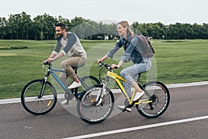 Happy couple riding bicycles together in park