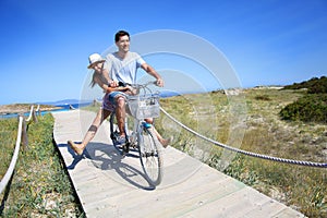 Happy couple riding bike by the seaside