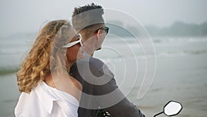 Happy couple riding motor bike on seaside at sunrise. Man, woman driving motorcycle on ocean coast. Pretty lady in