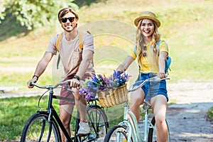 happy couple riding retro bicycles in park