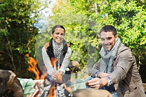 Happy couple roasting marshmallow over camp fire