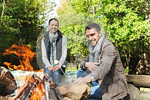 Happy couple roasting marshmallow over camp fire