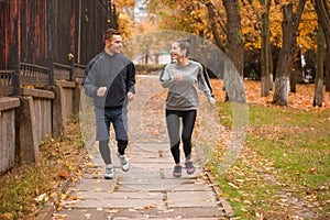 A happy couple runing in an autumn park. Outdoors.