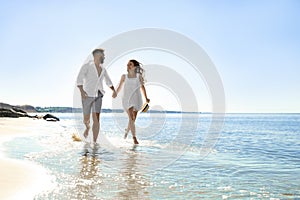 Happy couple running on beach near sea. Honeymoon trip