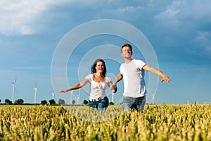 Happy couple running over grainfield