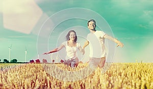 Happy couple running over grainfield