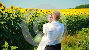 Happy couple running on sunflower field, taking hands and smiling.