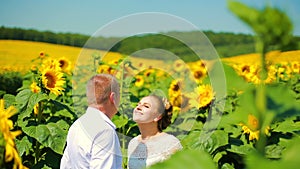 Happy couple running on sunflower field, taking hands and smiling.