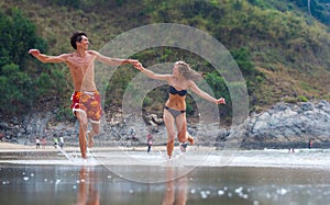 Happy couple runs along the beach