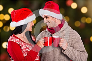 Happy couple in santa hat toasting coffee mugs