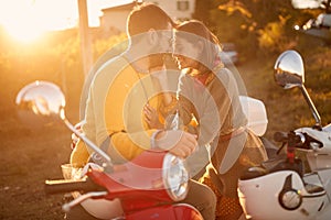 Happy couple on scooter enjoying in romantic road trip on vacation at sunset