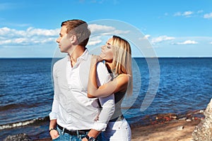 Happy couple on sea background. Happy young couple laughing and hugging on the beach