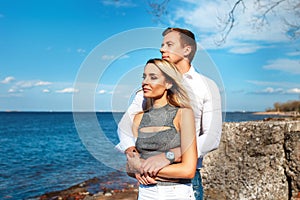 Happy couple on sea background. Happy young couple laughing and hugging on the beach