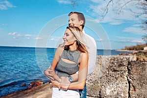 Happy couple on sea background. Happy young couple laughing and hugging on the beach