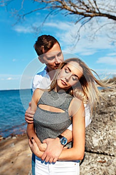 Happy couple on sea background. Happy young couple laughing and hugging on the beach