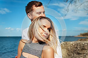 Happy couple on sea background. Happy young couple laughing and hugging on the beach