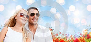 Happy couple in shades over poppy field background