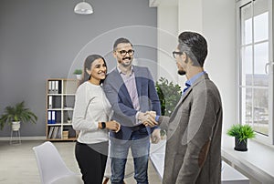 Happy couple shaking hands with a male business broker or insurance agent or investment adviser.