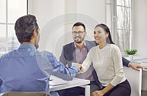 Happy couple shaking hands with a male business broker or insurance agent or investment adviser.