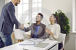 Happy couple shaking hands with a male business broker man or insurance agent or investment adviser