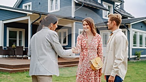 Happy Couple Shaking Hands with Realtor in Front of Their New Home. Professional Real Estate Agent