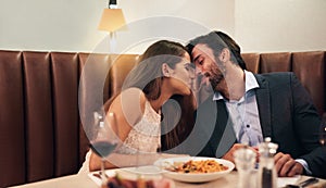 Happy couple, sharing food and kiss for dinner date, embrace or relationship romance at night in restaurant. Man and