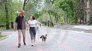 Happy couple with a shelter dog walking in the old city in summer 4k footage